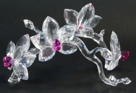 A Swarovski crystal floral display, depicting four flowers with pink coloured glass centres, on stylised bough, 21cm wide.