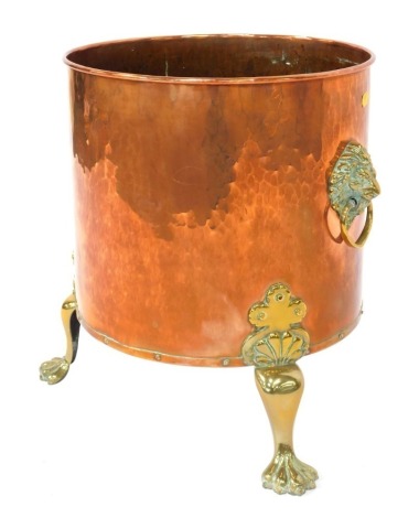 A Victorian copper and brass log bucket, cylindrical hammered form, with lion mask ring handles, raised on four lion paw feet, 46cm high.