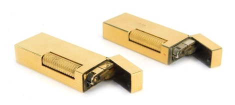 Two Dunhill pocket lighters, comprising one of square diamond design, the other of brushed overall design, with inner steel casings and brass finish, 6.5cm high. (2)