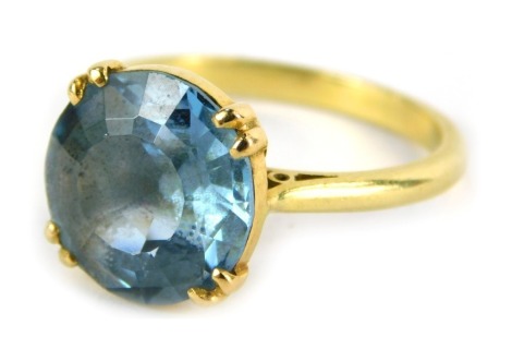 An aquamarine dress ring, the circular faceted aquamarine in four claw double setting, with pierced design shoulders, on a plain band, yellow metal unmarked, ring size O, 4.8g all in.