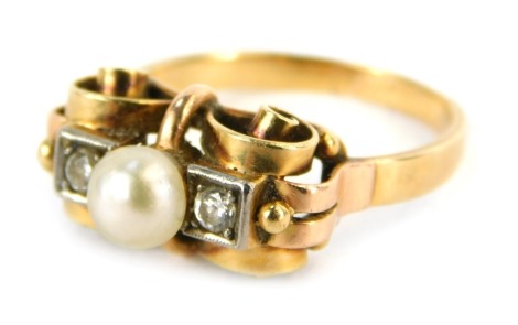 An Edwardian diamond and pearl set dress ring, the scroll central bow design set with central cultured pearl, flanked by two round brilliant cut diamonds each approximately 0.10ct, on a yellow and rose coloured band, unmarked, ring size O, 4.5g all in.