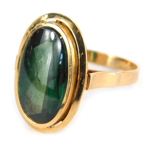 An oval designed dress ring, set with central dark green oval faceted stone, in a rub over setting, plain band, yellow metal stamped 585, size R 1/2, 6.5g all in.