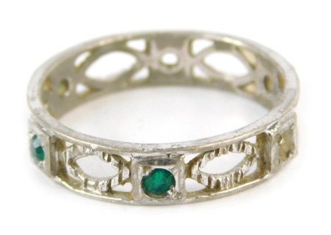 An eternity ring, of pierced design, set with green paste stones, white metal unmarked, size Q 1/2, 2.3g all in. (AF stones missing)