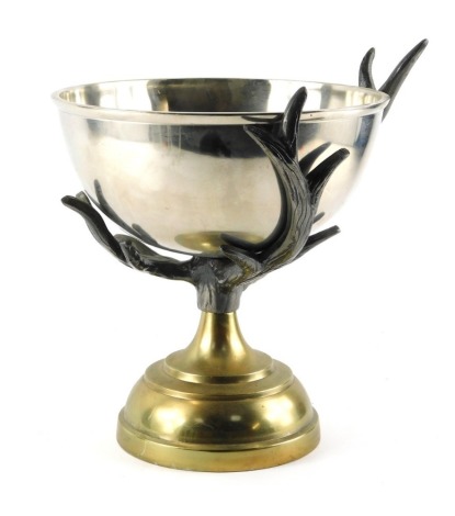 A 20thC centrepiece or wine cooler, with a rounded steel bowl supported by cast metal antlers, on a stepped brass circular base, 28cm high, 25cm diameter.