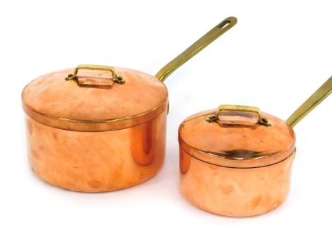 Two copper saucepans, each with a lid with brass handles, 21cm diameter, and 15cm diameter respectively.