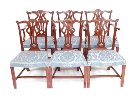 A set of six mahogany dining chairs in George III style, each with a shaped leaf carved rail, open splat back, overstuffed blue floral upholstered seat and front reeded legs.