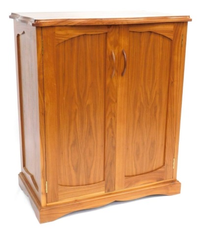 A modern walnut finish cupboard, with serpertine top above arrangement of two doors, with moulded handles, on a stepped base, 100cm high, 83cm wide, 52cm deep.