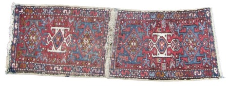 A pair of Heriz rugs, stitched together, each with three central medallions, against a red field, within repeating geometric borders, 164cm x 55cm overall.