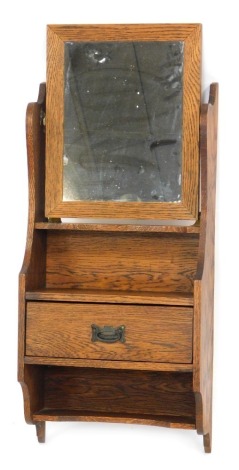 An Edwardian oak hanging wall shelf, the mirror top above two shelf sectional, with central single drawer, 83cm high, 36cm wide, 16cm deep.