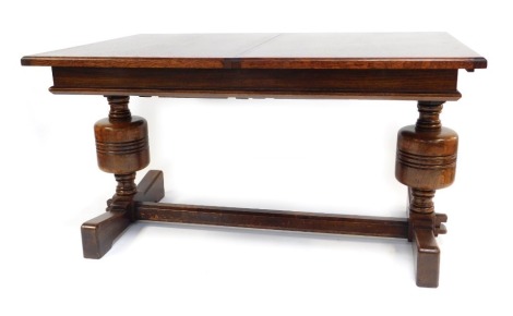 A 17thC style oak draw leaf dining table, with one additional leaf, raised on turned and cup and cover supports united by a stretcher, 76cm high, 136cm wide, 182cm extended, 90cm deep.