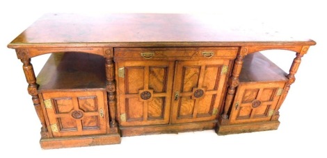 A Victorian burr elm Aesthetic movement sideboard, the rectangular top with a moulded edge, above a frieze drawer with brass drop handles and two doors with four panels and patera and elaborate hinges, flanked by a recess above a further drawer, supported