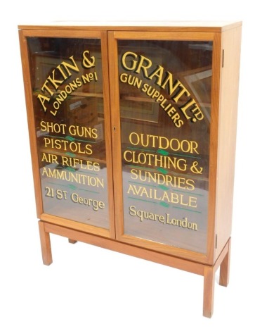 A teak two door display cabinet, with applied advertising for Atkin and Vrant Ltd Clothing and Gun supplies, 122cm high, 92cm wide, 28cm deep.