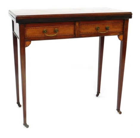 An Edwardian mahogany tea table, with marquetry central oval panel, folding top, above arrangement of two drawers on taper legs, terminating in castors, 75cm high, 75cm wide, 40cm deep.