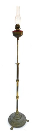 A 19thC brass oil lamp, with a cranberry glass reservoir, on tripod base, with glass funnel, 191cm high.