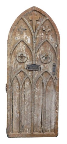 A Gothic style door, from Ketton Hall, Nr Stamford, the arched top with applied crest and flowers with arches, and a second central letter plate, 201cm high, (AF)