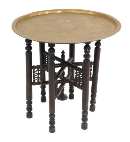 A Benares brass tray top table, on pierced wooden stand, 57cm high, 61cm diameter.