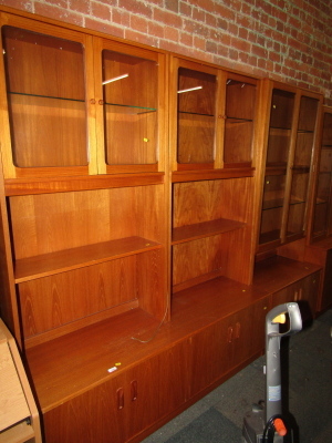 A G-Plan wall unit, the top with two pairs of glazed doors above a recess, the base with four cupboards, 188cm high, 160cm wide, 47cm deep, together with a similar narrow cabinet. (2)