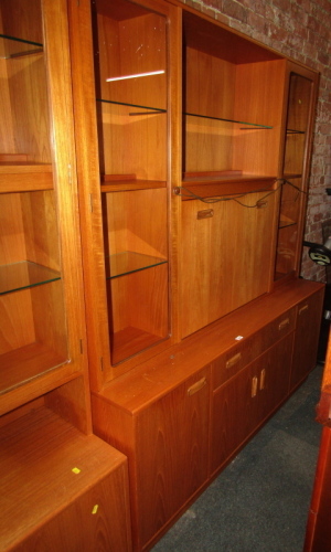 A G-Plan display cabinet, the top with an arrangement of recesses, glass fronted cabinets and a fall, the base with a frieze drawer above two cupboards flanked by two further cupboards, 183cm high, 160cm wide, 43cm deep.