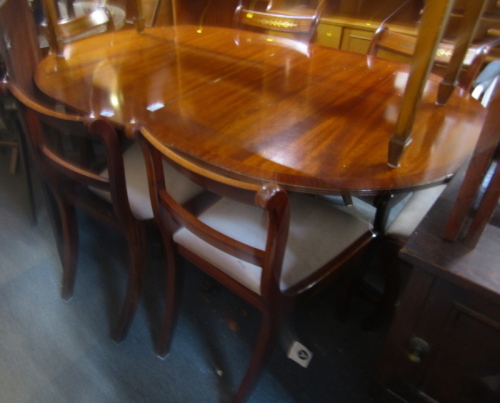 A mahogany and cross banded oval extending twin pedestal dining table, 80cm high, the top 140cm x 100cm, with additional leaf, 155cm wide, together with six dining chairs, with drop in seats (4 + 2).