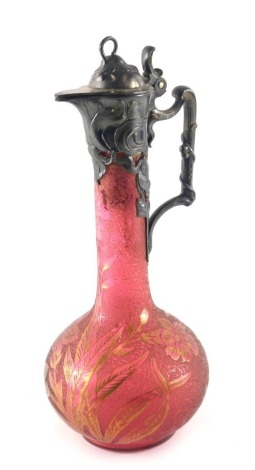 A WMF acid etched cranberry tinted glass and pewter mounted claret jug, the lid, handle etc. decorated with typical Art Nouveau scrolls, leaves, berries, etc. the glass, decorated with flowers and leaves, picked out in gilt, stamp to handle, 34cm high.