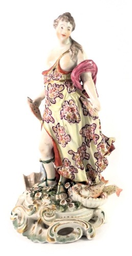 An 18thC Derby porcelain figure, modelled in the form of a lady holding a fish beside an urn, etc. on pierced rococo scroll base, 24cm high.