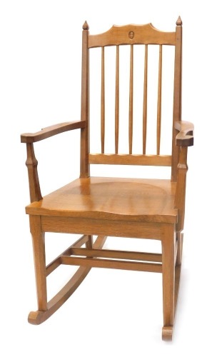 An Alan 'Acornman' Grainger oak rocking chair, with spindle turned back, solid seat and shaped arms, on faceted legs with rockers, in the manner of Mouseman.