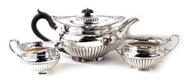 A George V silver three piece tea service, with shell capped beaded border, with fluted bodies, comprising teapot, milk jug, sugar bowl, the teapot with ebonised handle and knop, maker TB&S, Sheffield 1916, 42.53oz all in. (3)