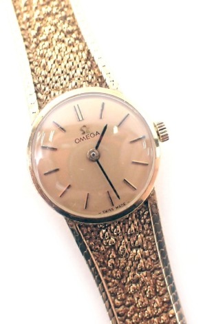 A 9ct gold Omega lady's wristwatch, the gold coloured circular dial, 1.5cm wide, on a bark effect bracelet, 24.8g all in.