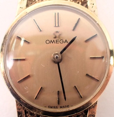 A 9ct gold Omega lady's wristwatch, the gold coloured circular dial, 1.5cm wide, on a bark effect bracelet, 24.8g all in. - 2