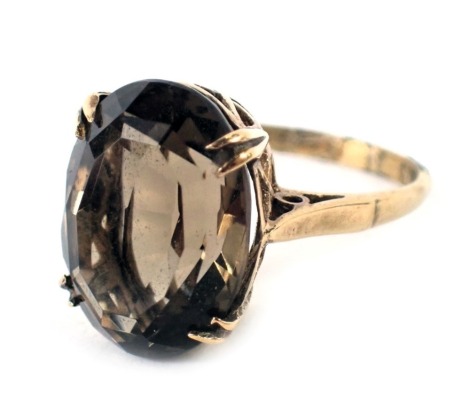 A 9ct gold smoky quartz dress ring, the oval smoky quartz in four double claw setting, in a raised basket on plain band, ring size M½, 4.5g all in.