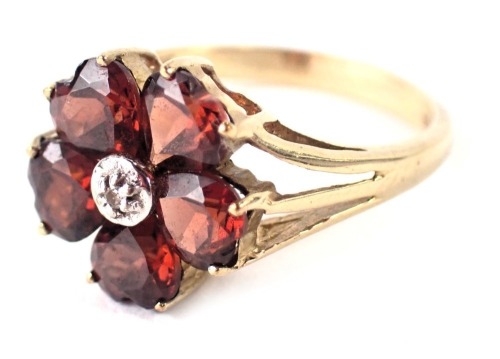 A 9ct gold cluster ring, the outer petals set with dark red heart shaped stones and a central CZ stone, in white gold border, ring size M½, 2.9g all in.