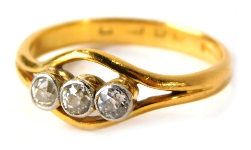 A 22ct gold three stone diamond dress ring, set with three old cut diamonds, in a rub over platinum setting, on yellow metal band stamped 22ct, ring size S½, 4.6g all in.