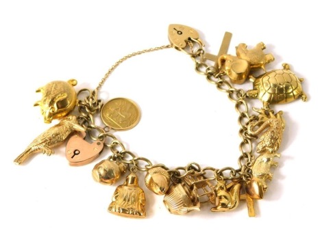 A 9ct gold charm bracelet, on curb link chain, with various charms to include cross, elephant, tortoise, hippo, anchor, rocking chair, teapot, acorn, seated Buddha, milk churn, woodpecker, pig, St Christopher pendant, and two heart shaped padlocks, with s