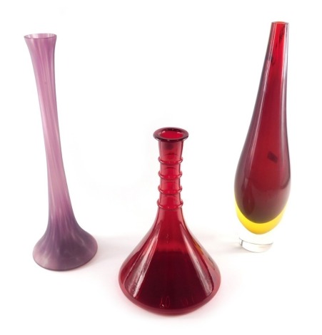 A large clear red and yellow slender Art Glass vase, 50cm high, a ship's decanter shaped ruby tinted glass vase, 33cm high, and a purple mottled glass vase, 48cm high.