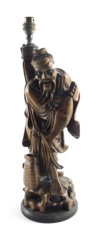 A late 19th/early 20thC Chinese carved lamp base, modelled in the form of a gentleman holding a fish, 50cm high.