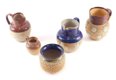 Three items of Doulton Lambeth stoneware, comprising relief moulded and blue glazed jug, 16cm high, gilt patterned bowl, 10cm high, and a brown treacle glazed jug, 8cm high, together with two Royal Doulton stoneware jugs, comprising a light brown and dark