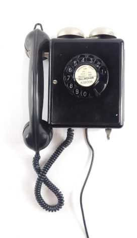 A black plastic wall mounted telephone, with two chrome plated bells.