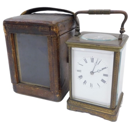 A late 19th/early 20thC French gilt brass carriage timepiece, with a hinged handle, the white enamel dial decorated with Roman numerals, in fitted leather travelling case, 18cm high.