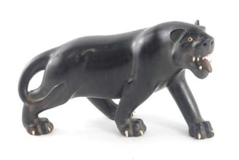 An early 20thC carved ebony figure of a lion or panther, with bone teeth, eyes and claws, 18cm long, possibly India.