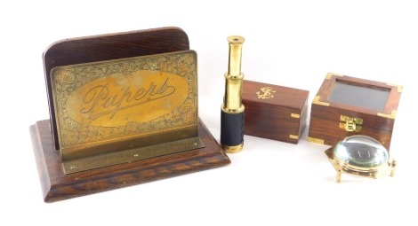 An oak and brass letter or stationary rack, engraved Papers, 26cm wide, an Indian brass telescope in hardwood case, and a similar magnifying glass.