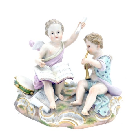 A late 19thC Meissen porcelain figure group, modelled in the form of a putto playing music, etc., on a rococo scroll ovoid base, blue cross swords mark to underside and numbered 2464, 17cm wide. (AF)