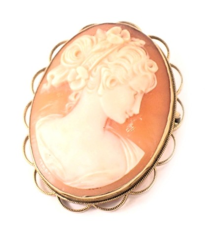 A 9ct gold framed shell cameo brooch, depicting maiden looking dexter, with curl and flower head dress, with a petalated border, 3.5cm x 3cm, 8.9g all in.