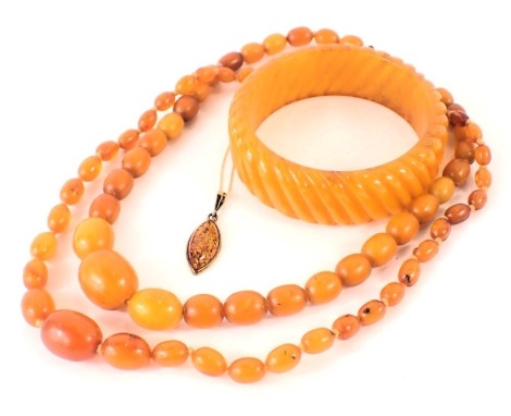 A group of amber jewellery, comprising a 9ct gold imitation amber pedant and chain, the pendant with amber flecks, in a yellow gold frame, stamped 375, on fine link neck chain, 3g, two butterscotch amber beaded necklaces on string strands, 40.9g all in, a