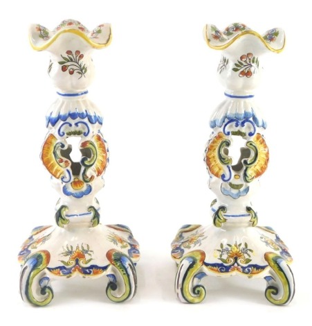 A pair of 19thC Formaintraux Frere Desveres Faience candlesticks, with pierced centre, decorated overall with scrolls, flowers, etc., 25cm high.