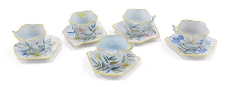 A set of five Porquier Beau Faience botanical cups and saucers, each with a shaped edge, handwritten mark to underside.