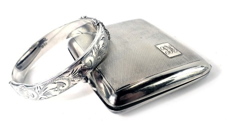 Two items of silver, comprising a silver hinged bangle, and a George V silver cigarette case, of engine turned decoration with a rectangular panel, bearing the initials RCC, Birmingham 1927, 3.40oz. (2)