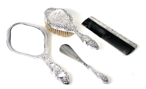 A four piece matched dressing table set, comprising hand mirror and brush, each with embossed detail of figures of family with mandolin, a later comb, and a silver handled button hook.