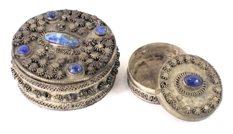 Two eastern white metal dressing table jars, each set with lapis lazuli unmarked, 7cm and 4.5cm wide. (2)