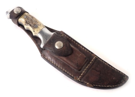 A hunting knife, by RH Ruana of Bonner, Montana, with antler style handle and leather scabbard, 28cm long.