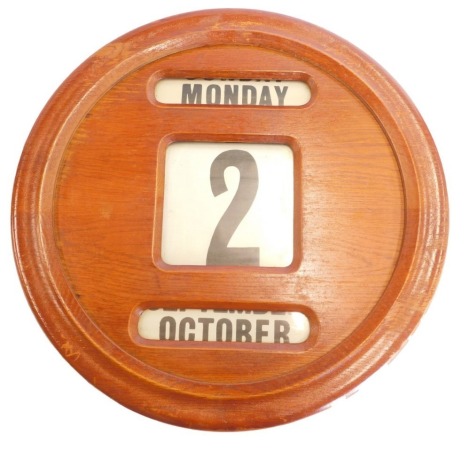 An oak cased wall calendar, with day, date and month reels, 41cm diameter.